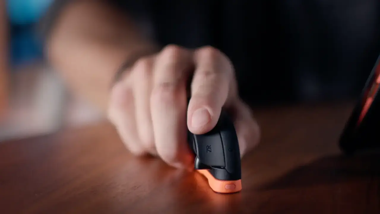 A hand using a Joy-Con 2 flat against a table for mouse-style control