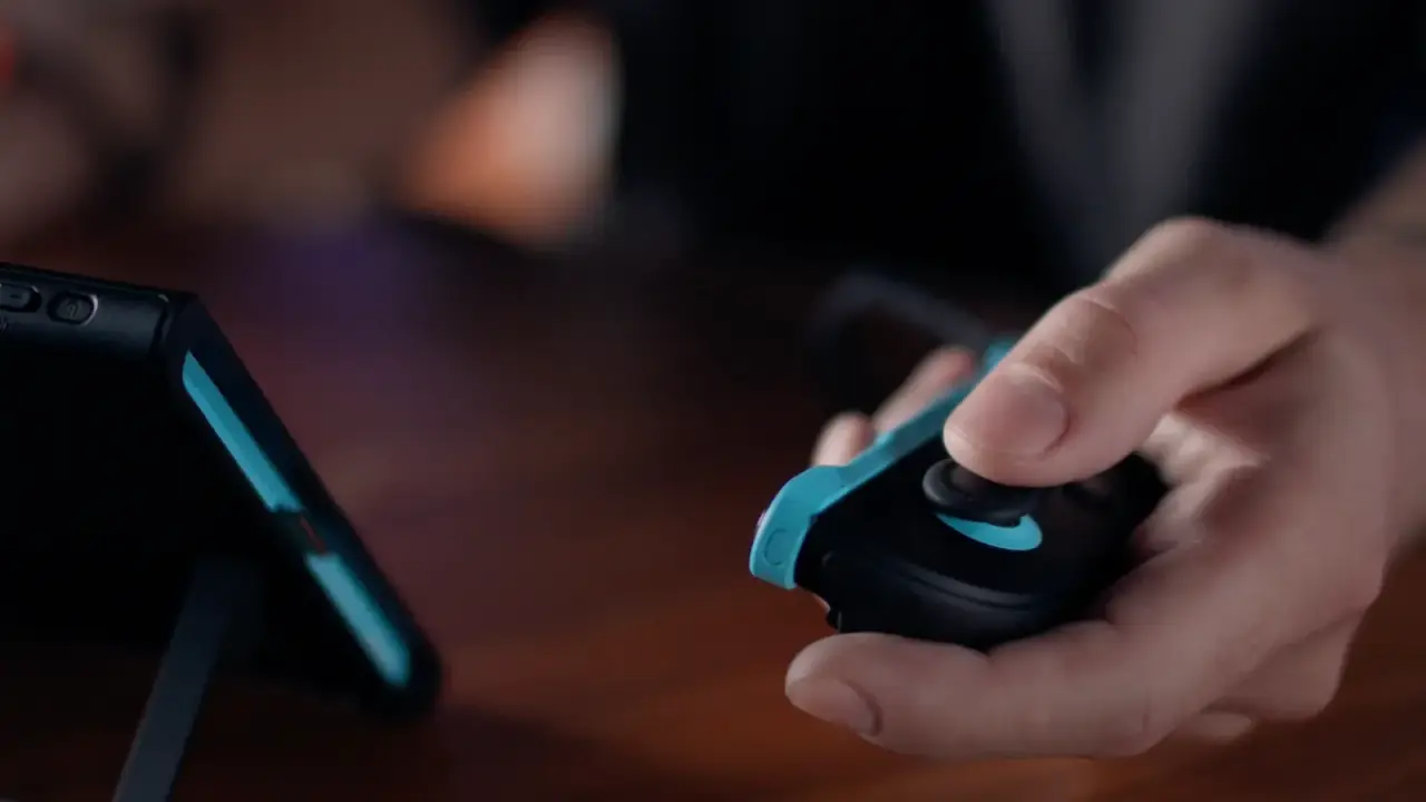 A player holding a detached Joy-Con 2 beside the Switch 2 display
